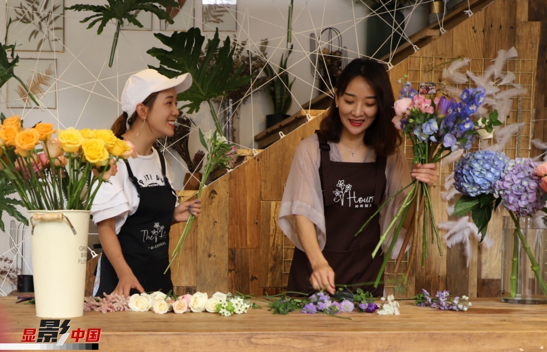 “昆明是鮮花的原產地，有亞洲最大的鮮切花交易市場，可以說具備開花店的天時地利；另外和很多女孩一樣，我從小也就有開花店的夢想！”說起當初的決定，王黎媛說一是因為夢想，另外也跟昆明這個城市產花、賣花的“基因”有關。圖為王黎媛和同事在制作花束。新華網 周亞平/攝 念新洪/文
